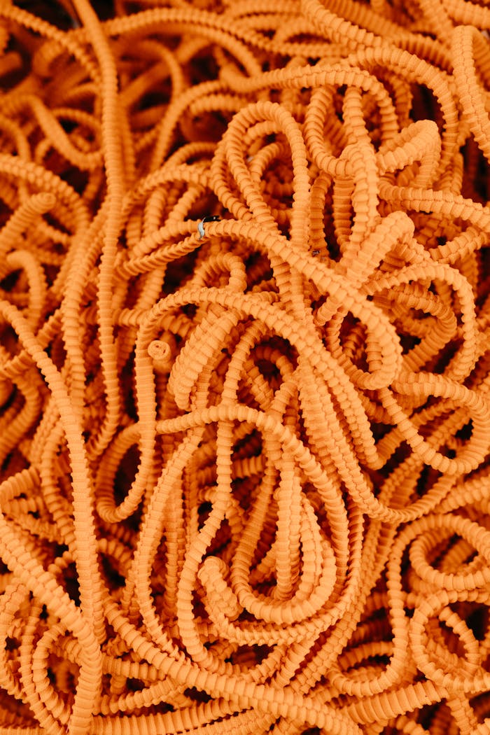 Vibrant orange cables create a dense, tangled texture, perfect for abstract backgrounds.